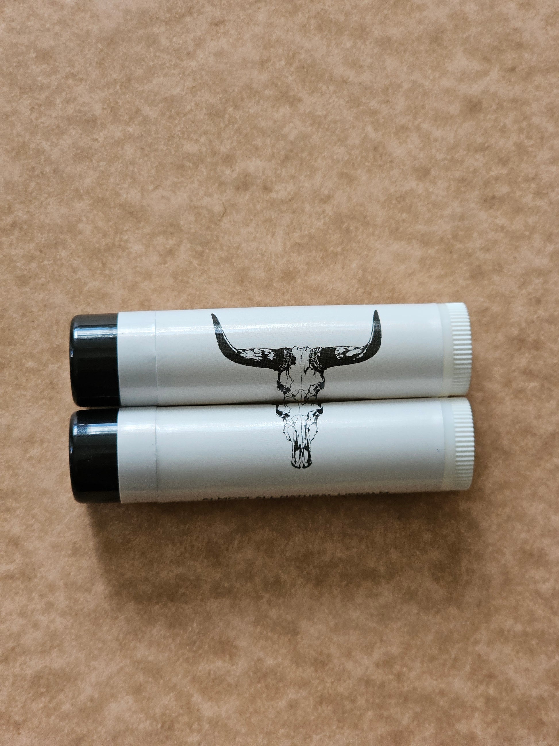 Black sihilloute of a adhorn bull skull on a white back ground wrapped around a lip balm tube. 