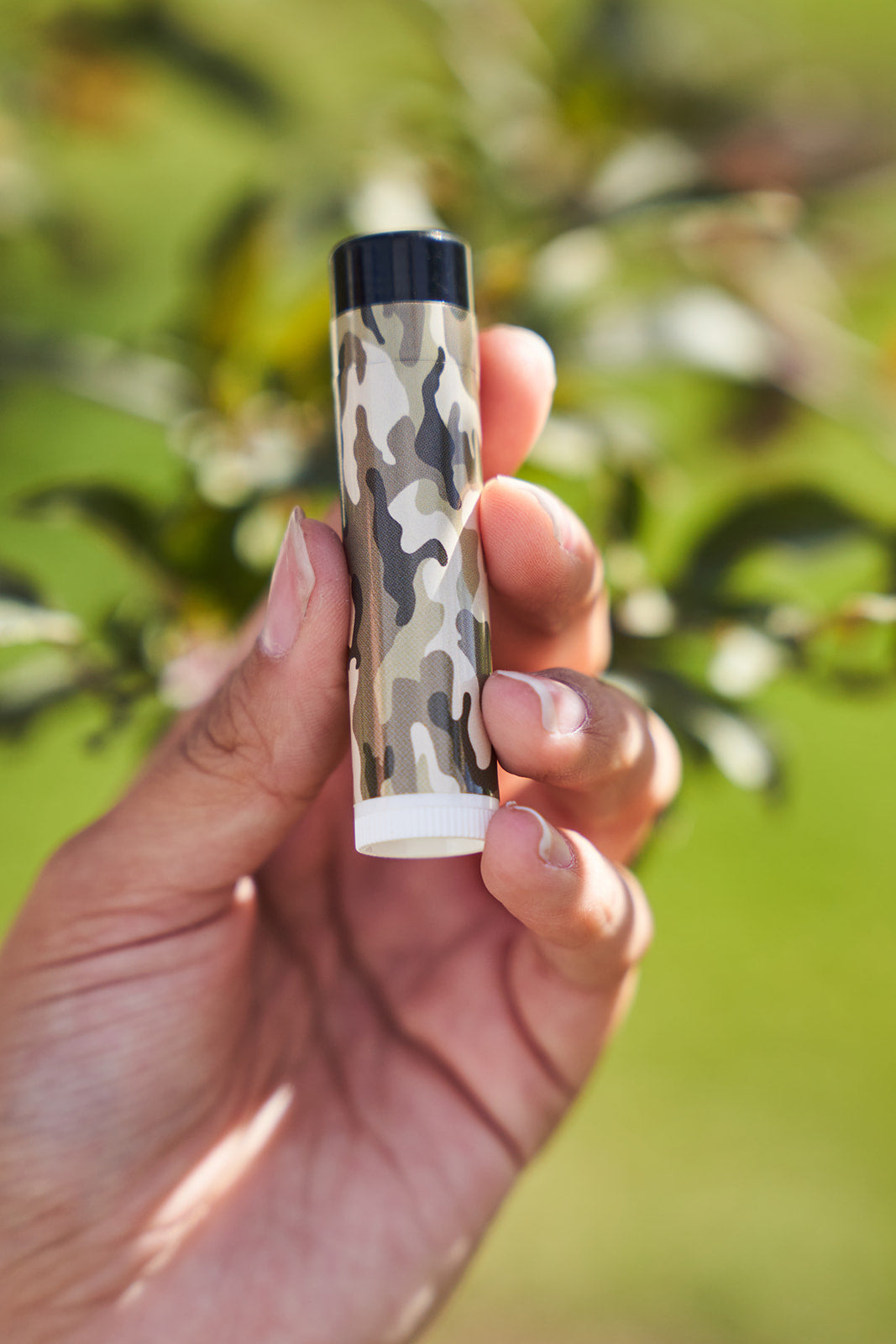Camo lip balm held on a hand. Hunting gear. Hunting accessories. 
