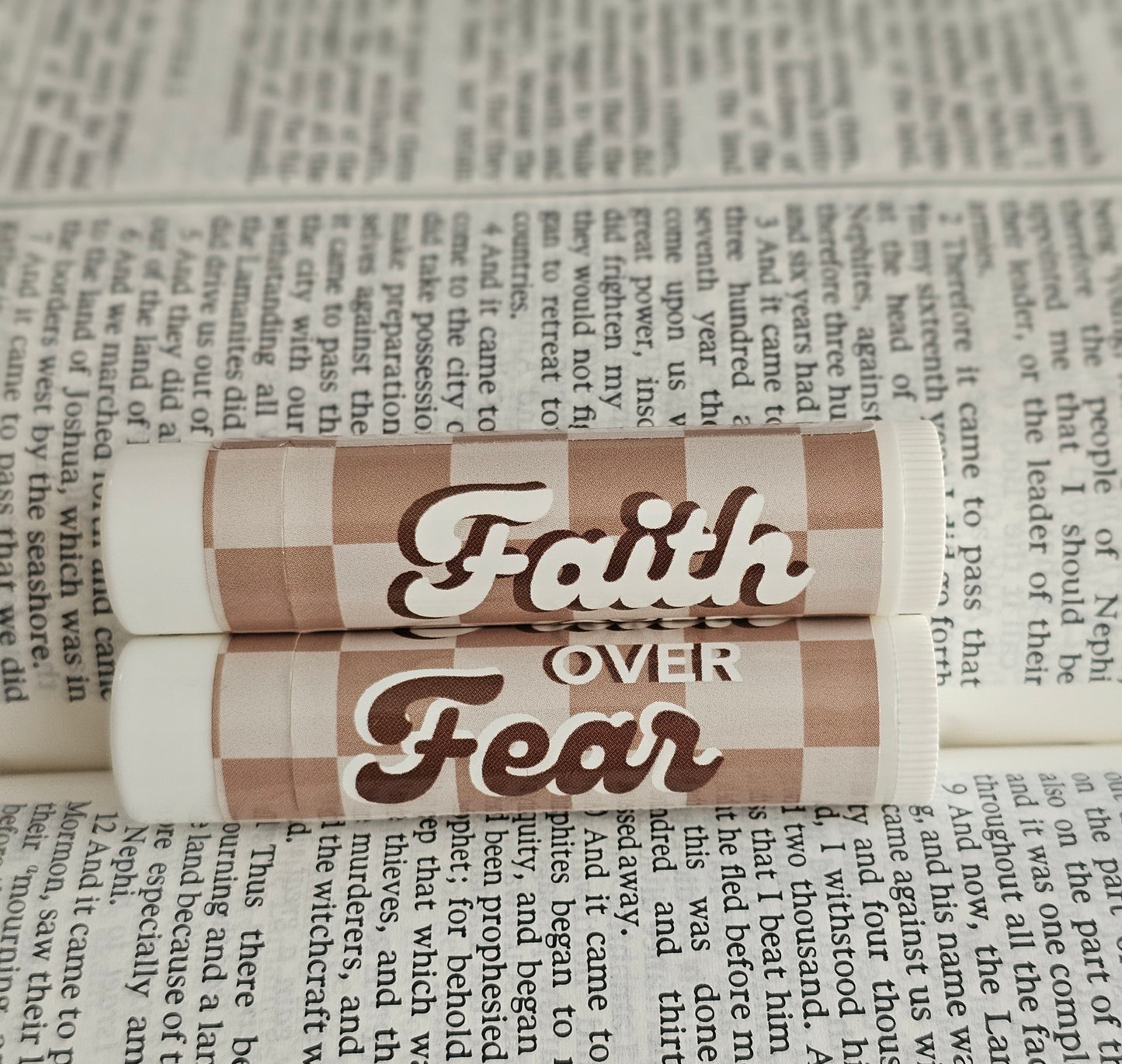 Brown and tan checkered background that says faith over fear in a groovy font. Laid on open scriptures. 