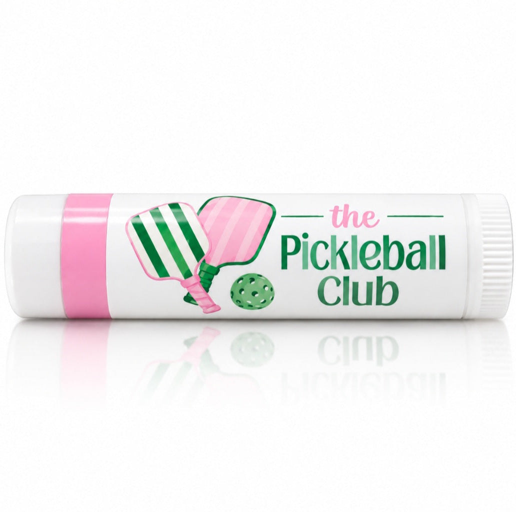 White custom lip balm featuring a pink and green Pickleball Club design with crossed pickleball paddles and ball.